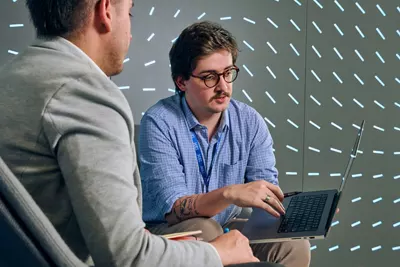 View of two professionals engage in a focused discussion within a modern office space. 